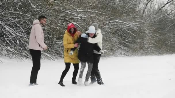 Молодые друзья веселятся со снегом в зимнем лесу — стоковое видео