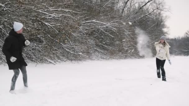 幸せな若いカップルは冬の森の中で雪玉と遊ぶ — ストック動画