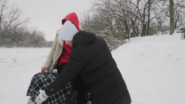 Casal jovem posando com moto ATV Quad na floresta de inverno. Homem com um chapéu branco cobriu sua namorada com cobertor — Vídeo de Stock