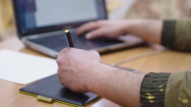 Side view of man draws and works at a computer using a graphics tablet — Stock Video