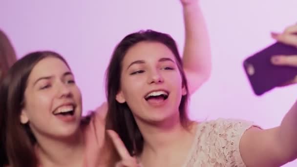 Four happy pretty young women in pajamas sits on bed, sings and records video on their phones at bachelorette party — Stock Video