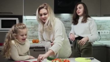 Genç anne ve iki kızı mutfakta salata pişiriyor. Anne tuzlu salata. Tuzlu bae.