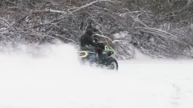 ATV Dörtlü bisikleti karda sürükleniyor. Kar tarlasında dört tekerlekli bisiklet süren bir sürücü..