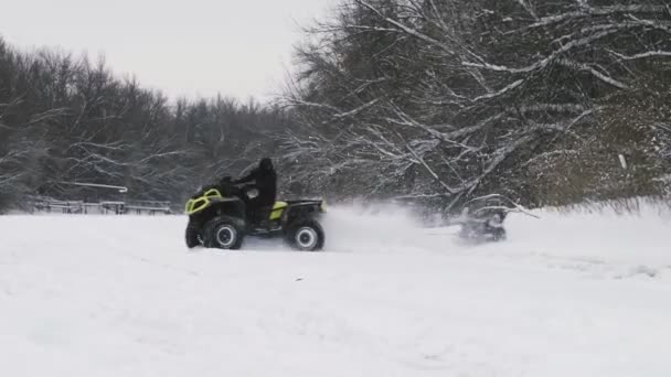 Kolo ATV Quad se vznáší na sněhu. Muž na čtyřkolce tahá ženu na snowtube na zamrzlé řece v zimě — Stock video