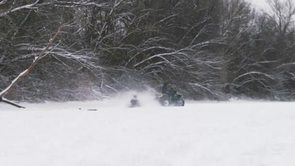 ATV Quad bike à deriva na neve. Homem em quadriciclo puxa mulher em tubo de neve em rio congelado no inverno — Vídeo de Stock