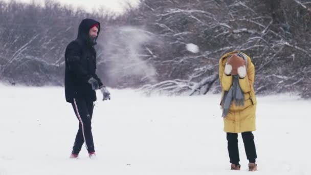 Glada unga par leker med snöbollar i vinterskogen — Stockvideo