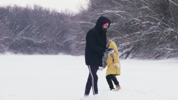 若いカップルは冬の森の中で雪玉と遊ぶ — ストック動画