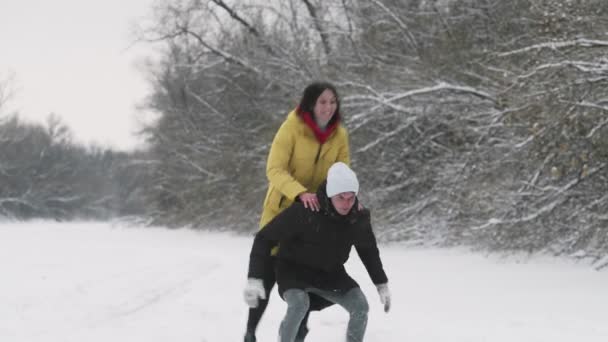 若い幸せなカップルは冬の森で雪と楽しみを持っています — ストック動画