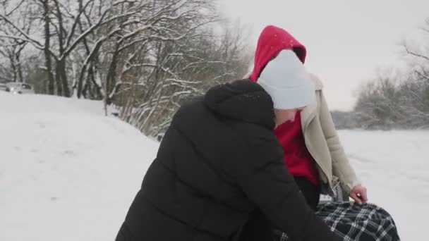 Fiatal pár pózol ATV Quad kerékpárral a téli erdőben. Egy fehér kalapos férfi takaróval takarta be a barátnőjét. — Stock videók