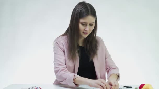 Atractiva joven mujer prepara hilo a rebordear en la mesa en un estudio blanco — Vídeo de stock