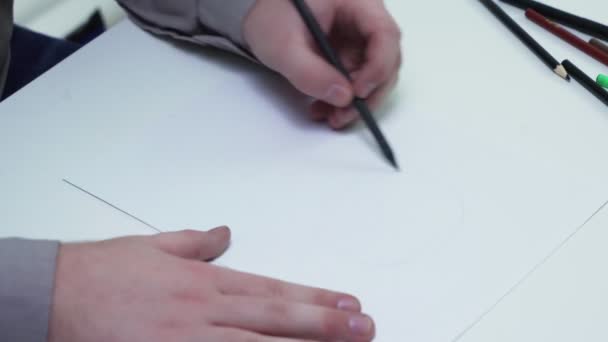 Vue du dessus de l'homme utilise un crayon pour dessiner un visage de filles sur le papier à la table — Video