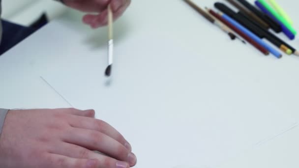 흰 스튜디오 에 있는 탁자 위에 놓인 백지 위에서 물감으로 그림을 그리는 화가의 맨 위 사진 — 비디오