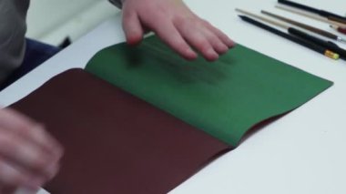 Beyaz bir stüdyodaki masada yeşil renkli bir kağıda çizgiler çizmek için üst görünüm kalem ve cetvel kullanır.