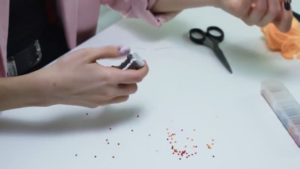 Közelkép a nő készíti fém vonal gyöngyözés az asztalnál egy fehér stúdió — Stock videók