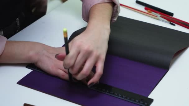 Horní pohled ženy používá tužku a pravítko pro kreslení čar na barevný papír u stolu — Stock video