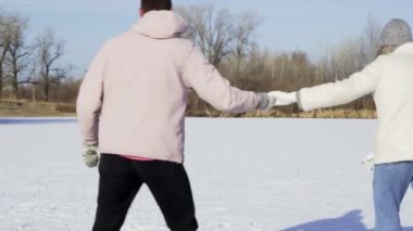 Genç çift ormanda donmuş gölde buz pateni yapıyor.