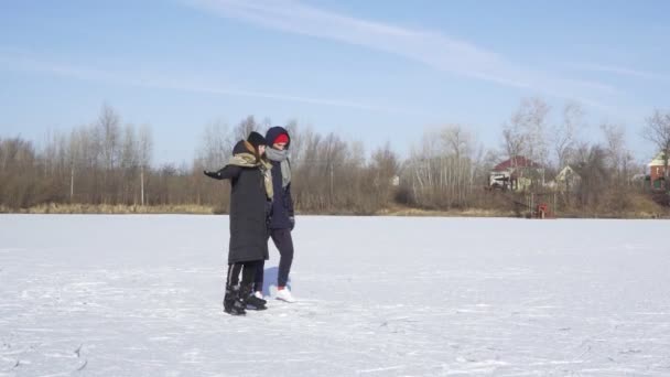 Młody mężczyzna i jego dziewczyna do jazdy na łyżwach na zamarzniętym jeziorze w lesie — Wideo stockowe