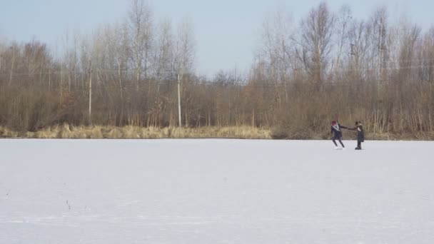 Genç adam koşar ve ormanda buz pateni yapan kız arkadaşını çeker. — Stok video
