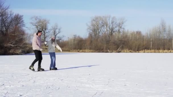 Giovane coppia cavalcare pattinaggio su ghiaccio insieme sul lago ghiacciato nella foresta — Video Stock