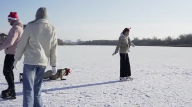 Genç mutlu arkadaşlar ormanda büyük donmuş bir gölde birlikte buz pateni yapıyorlar.