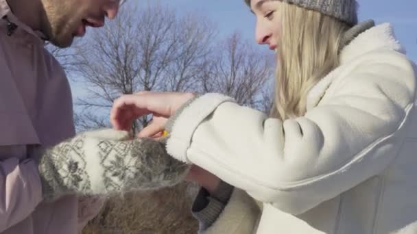 Pareja joven limpia y come mandarina en el bosque de invierno — Vídeos de Stock