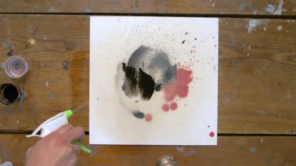 Vista superior de dois artistas são pinturas um quadro abstrato: um derrama algumas gotas de dor negra para lona e secador de segunda usa — Vídeo de Stock