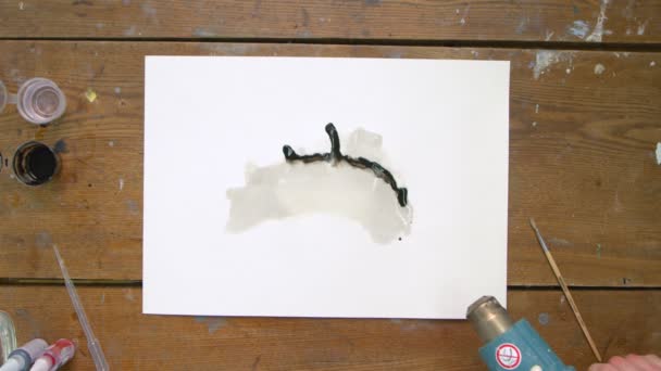 Üç sanatçının üst görüntüsü soyut bir resimdir: biri tuvale birkaç damla siyah acı döker, ikinci sanatçı bu boyayı taşımak için su spreyi kullanır ve üçüncüsü kurutucu kullanır — Stok video
