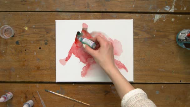 Ovanifrån av två konstnärer är färger en abstrakt bild: en häller några droppar grön smärta till våt duk och andra använder pensel för att distribuera den — Stockvideo