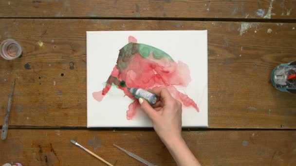 Vista dall'alto di artista femminile dipinge un quadro astratto, versa alcune gocce di dolore verde su tela bagnata e utilizza asciugatrice per distribuirlo — Video Stock