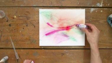 Ressamın üst görünüşü soyut bir tablo çizer, ıslak tuvale mor boya ile soyut şekiller çizer.