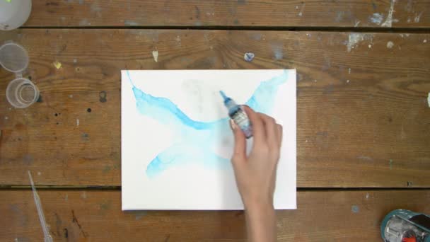 Vista dall'alto dell'artista dipinge un quadro astratto, dipinge forme astratte con vernice blu su tela bagnata — Video Stock