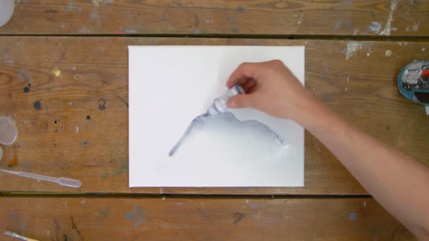 Top view a férfi művész fest egy absztrakt képet, ő öntött néhány csepp fekete festék nedves vászon és használja ecsettel terjeszteni — Stock videók