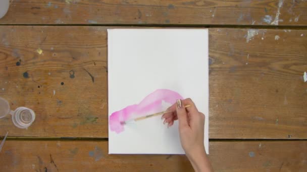 Top view női művész fest egy absztrakt képet, ő használ ecsetet terjeszteni rózsaszín festék nedves vászon — Stock videók