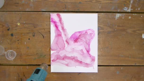 Arte Fluida. Pintura rosa abstrata. Vista superior da artista feminina usa secador para mover uma tinta rosa e secar sua nova imagem rosa — Vídeo de Stock