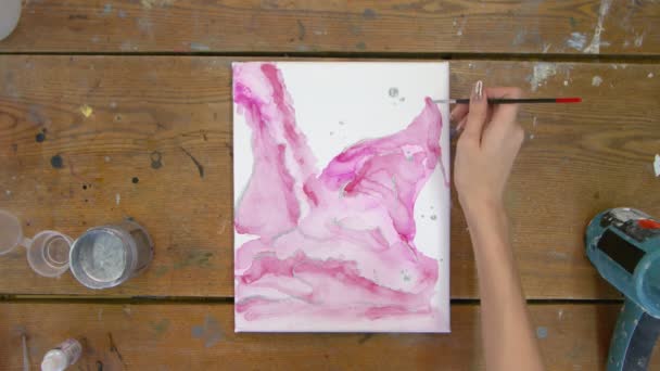 Arte fluido. Pintura rosa abstracta. Vista superior de artista femenina utiliza pincel y pintura plateada para dibujar un cuadro abstracto — Vídeo de stock