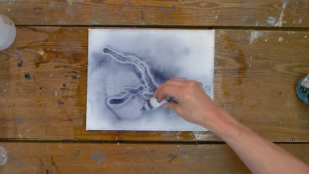 Ovanifrån av manliga konstnären målar en abstrakt bild, han målar med svart färg från röret och använder torktumlare för att flytta och torrt vatten med svart färg — Stockvideo