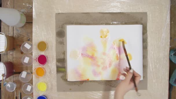 Draufsicht der Künstlerin malt Pastellfarbstoff-Bild mit gelben und orangefarbenen Farben auf nasse Leinwand. Fluidkunst. — Stockvideo