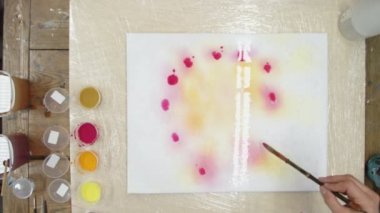 Erkek ressamın üst görüntüsü Pastel kravat boyası ya da Pastel kıvrımlı resimde ıslak tuval üzerinde kırmızı daireler çizer. Sıvı Sanat.