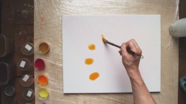 Erkek ressamın üst görüntüsü Pastel kravat boyası ya da Pastel kıvrımlı resmi ıslak tuval üzerinde turuncu boya ile boyar. Sıvı Sanat.