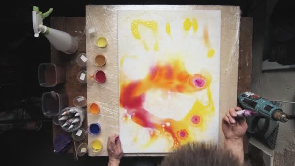 Vista superior de artista masculino pinta un cuadro abstracto, se vierte un montón de pocas gotas de pintura roja a la lona húmeda — Vídeo de stock
