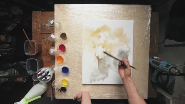 Ρευστή τέχνη. Αφηρημένη πολύχρωμη ζωγραφική. Κάτοψη του αρσενικού καλλιτέχνη χρησιμοποιεί πινέλο για να ζωγραφίσει όμορφα μαύρα αφηρημένα σχήματα σε βρεγμένο καμβά — Αρχείο Βίντεο