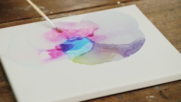 Vätskekonst. Abstrakt färgglad målning. Närbild av kvinnliga konstnären häller vatten till duk och använder pensel för att distribuera den — Stockvideo