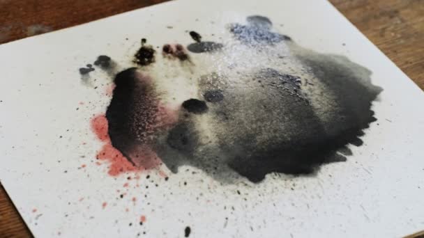 Primo piano di artista dipinge un quadro astratto, versa alcune gocce di vernice nera su tela e utilizza spruzzi d'acqua per spostare quella vernice — Video Stock