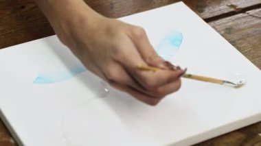 Sıvı Sanat. Soyut renkli tablolar. Kadın ressamın kopyaları tuvale boya fırçasıyla su dağıtır.