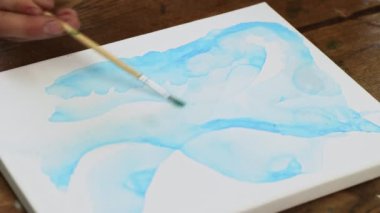 Sıvı Sanat. Soyut renkli tablolar. Kadın ressamlar tuvale mavi şekilli su dağıtmak için boya fırçası kullanır.