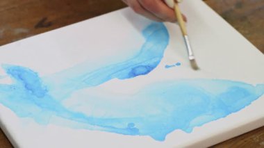 Sıvı Sanat. Soyut renkli tablolar. Kadın sanatçıya yakın çekim yap. Suyu ıslak tuvale mavi boyayla dağıt.