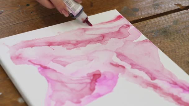 Close-up de artista feminina pinta um quadro abstrato, ele derrama um tubo de espuma de tinta rosa em telas molhadas — Vídeo de Stock
