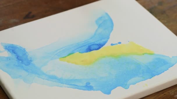 Folyékony művészet. Absztrakt kék és sárga festmény. Közelkép a női művész használ vízpermet keverni sárga és kék festékek — Stock videók