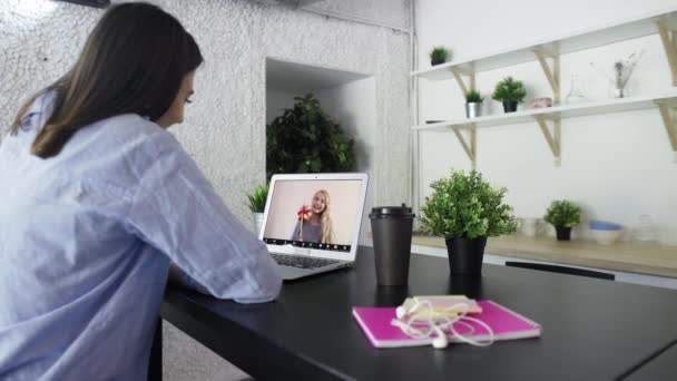 Mujer morena joven está hablando en una videollamada con un amigo utilizando el ordenador portátil en la cocina del hogar — Vídeos de Stock