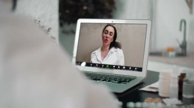 Terapist kardiyolog, hastaya video çağrısı ile tıbbi kalp hastalıkları danışmanlığı, hastanın omzunun üzerinden dizüstü bilgisayar görüntüsü sunar.